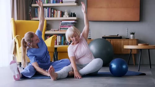 Woman Assists Senior with Stretching Exercises at Home