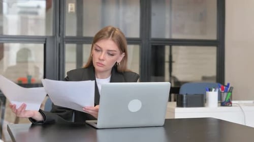 Focused Young Woman Working with Laptop and Documents