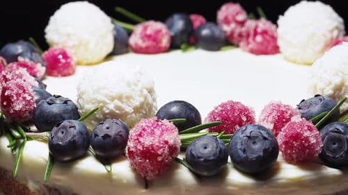 cake with white cream, blueberries and cranberries with rosemary, candies with coconut. close-up, sl