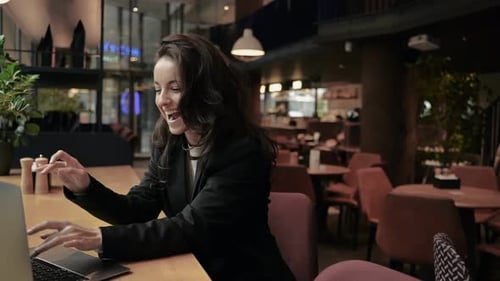 Glückliche zufriedene Frau benutzt Laptop, während sie im Café sitzt und arbeitet