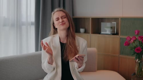 Disappointed Woman Sitting with Phone in Living Room