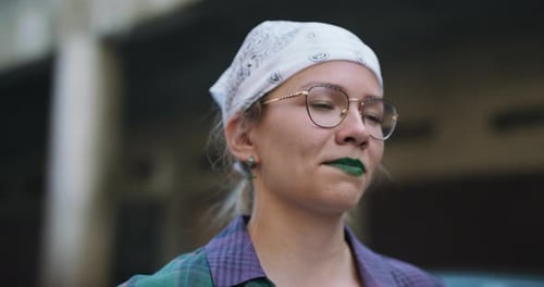 Ein junges Teenager-Mädchen mit Brille und Kopftuch auf dem Kopf steht in den Garagen des Anwesens herum