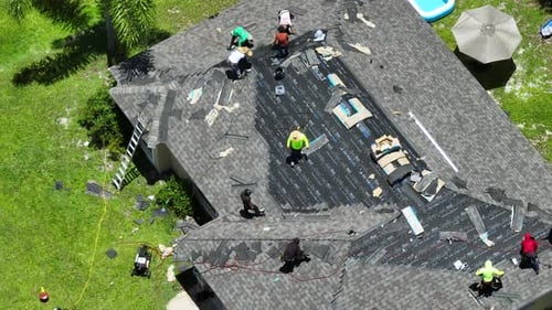 Construction Workers Installing Asphalt Shingles As House Roof Covering Building of Florida Home