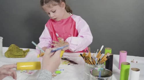 Little Girl Paints Cardboard Tubes at Home