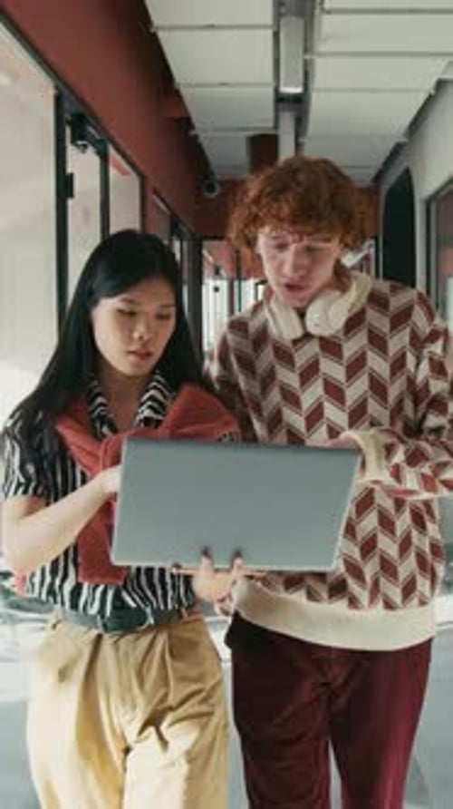 Students Walk Hallway with Laptop and Paperwork