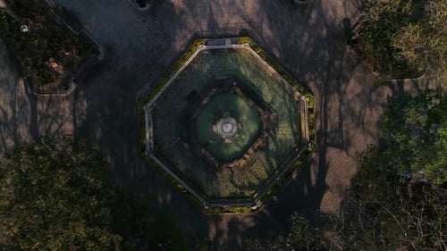 Explore an exquisite symmetrical fountain from above, surrounded by lush greenery.