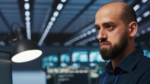 Close Up on Programmer in Server Farm Safeguarding Data