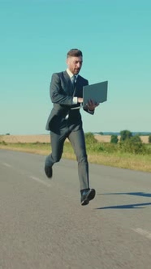 A Businessman is Energetically Running with His Laptop While Navigating an Open Road
