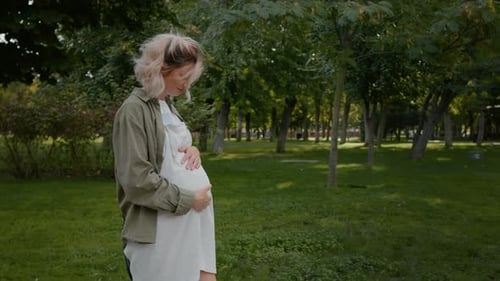 Side view of walking pregnant female outside.