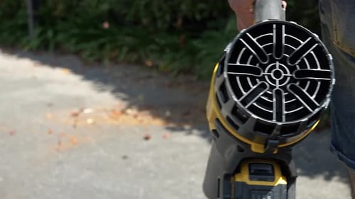 Close-up of a leaf blower that blows dead leaves onto the asphalt to clean the streets