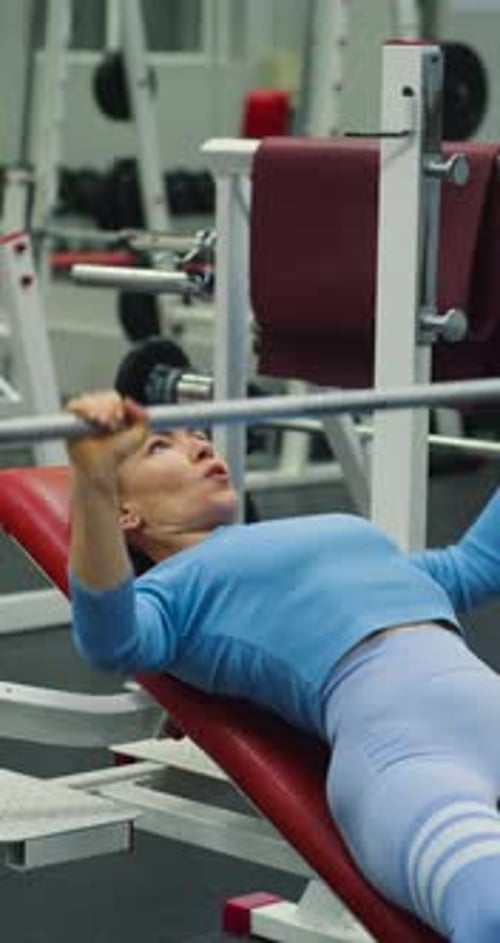 Woman Does Bench Press Exercise at Gym