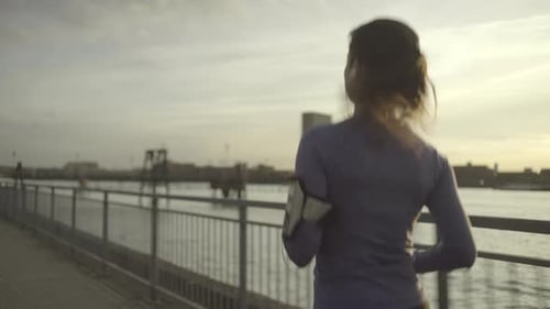 Female runner jogging by river Thames, London
