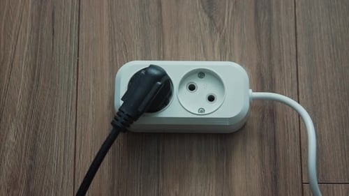 Branchez à la main une prise d'alimentation noire à plusieurs prises blanches en intérieur au Ralenti