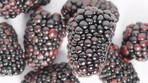 The view is from above as the blackberry rotates, while other berries are seen below.