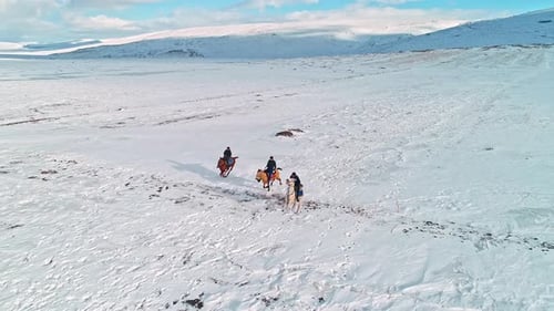 Horseback Riders Racing Across Snowy Plain