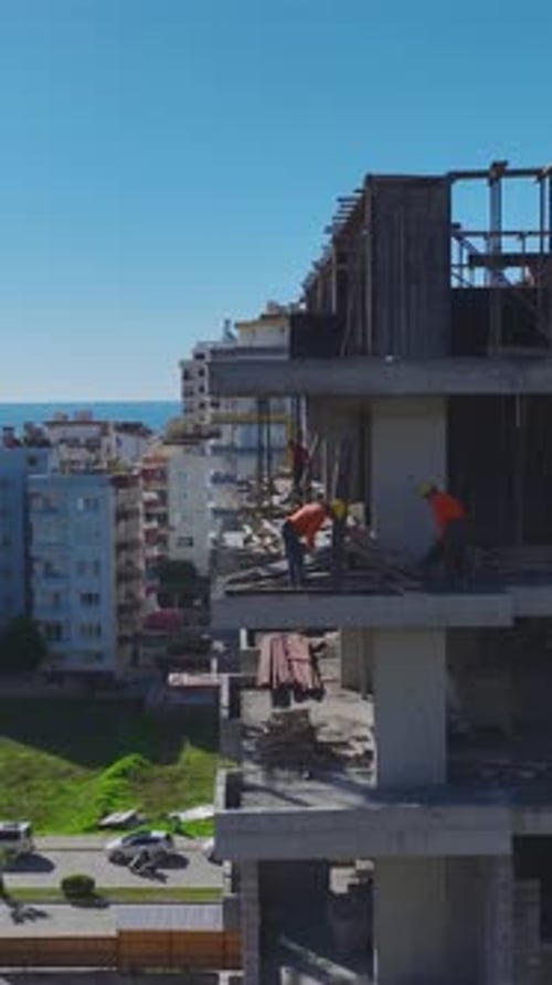 Vídeo vertical de trabajos de construcción activos con vertido de hormigón y montaje de estructuras metálicas