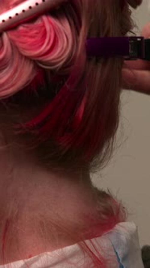 Hairdresser applies red color to blonde hair