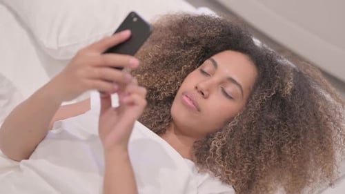 Young Woman Using Phone Lying in Bed