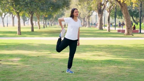 Woman Stretches and Runs in Grassy Urban Park