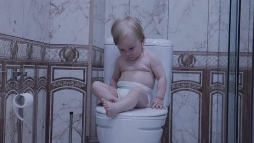 O bebê está sentado no banheiro