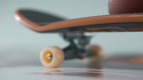 A hyper detailed shot of a mini skateboard, tiny white wheels, riding fingerboard from right to left