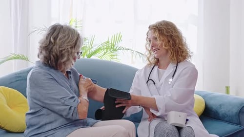 Friendly Doctor Measuring Blood Pressure of Senior Woman