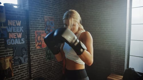 Focused Woman Boxing in Gym with Brick Wall