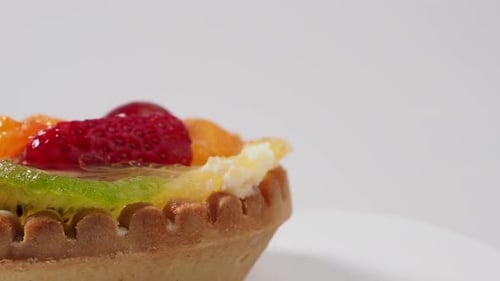 Pasteles giratorios con frutas sobre fondo blanco.