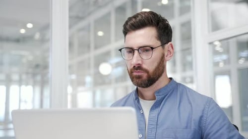 Thoughtful businessman working on laptop in business office. Manager thinking about problem solving