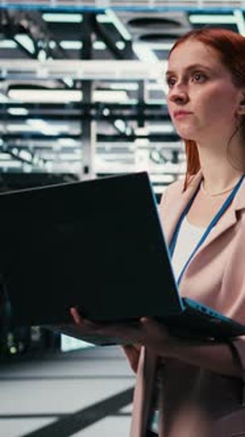 Vertical Video Woman in Modern High Tech Server Hub Using Notebook to Do Maintenance