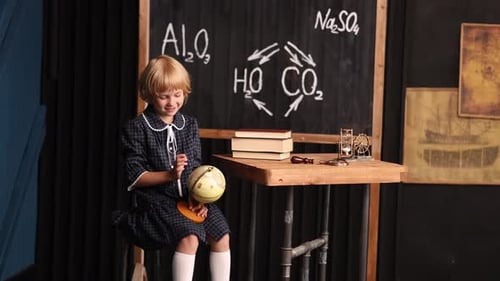 Girl Studies Globe in School Classroom Setting