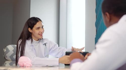 Female doctor showing digital tablet x-ray results to an African American colleague in a hospital