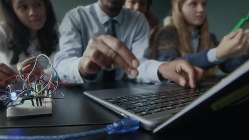 Profesor de programación escribiendo en el teclado del portátil durante la lección