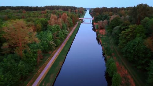 Ich fliege über den Spiegelkanal mit einer Brücke darüber. Rund um den Kanal wachsen tiefe Wälder.