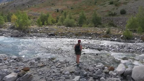 Gorgeous wide angle on a young Caucasian woman at the edge of a powerful river