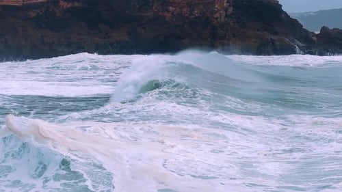 Dynamic Ocean Waves Powerfully Crashing Against Rocky Shoreline