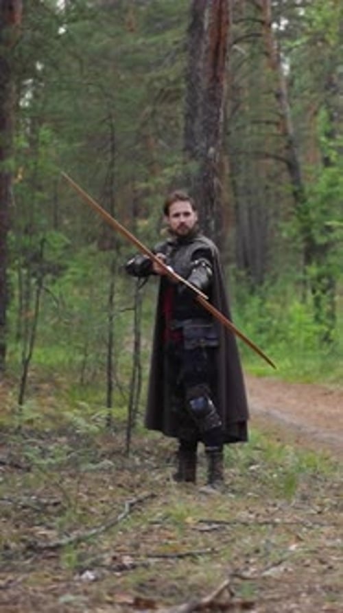 Warrior with Cape Shoots Bow Looking Around in Forest