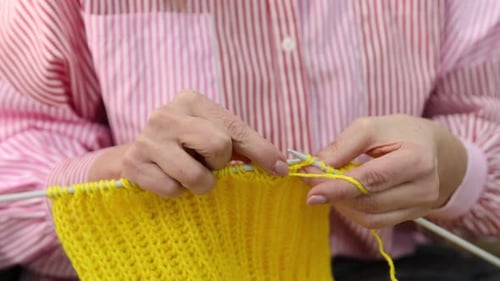 Woman Knitting Bright Yellow Yarn with Needles