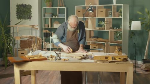 Senior Craftsman Smoothing Wood in Workshop