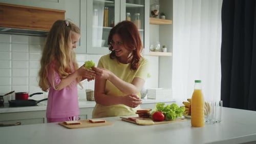 Mother and Daughter Make Sandwiches Together in Kitchen