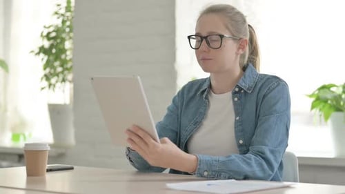 Beautiful Young Woman Using Tablet While Sitting in Office