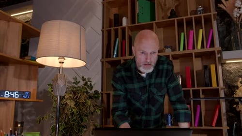 Positive Middle Aged Male Entrepreneur Networking on Laptop at Home Office