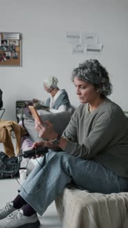 Mature Female Refugee Making Phone Call in Emergency Shelter