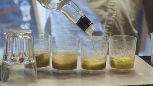 Barman pouring alcohol into four cups in a bar