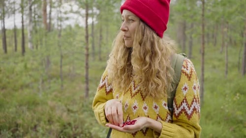 Woman Enjoys the Simple Pleasure of Eating Handpicked Berries in the Tranquil Setting of a Pine