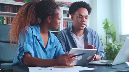 Young Adults Collaborating on Tablet and Laptop in Office