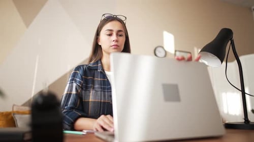 Girl in Home Office on Table at Place of Work Opens Laptop Screen and Starts Working