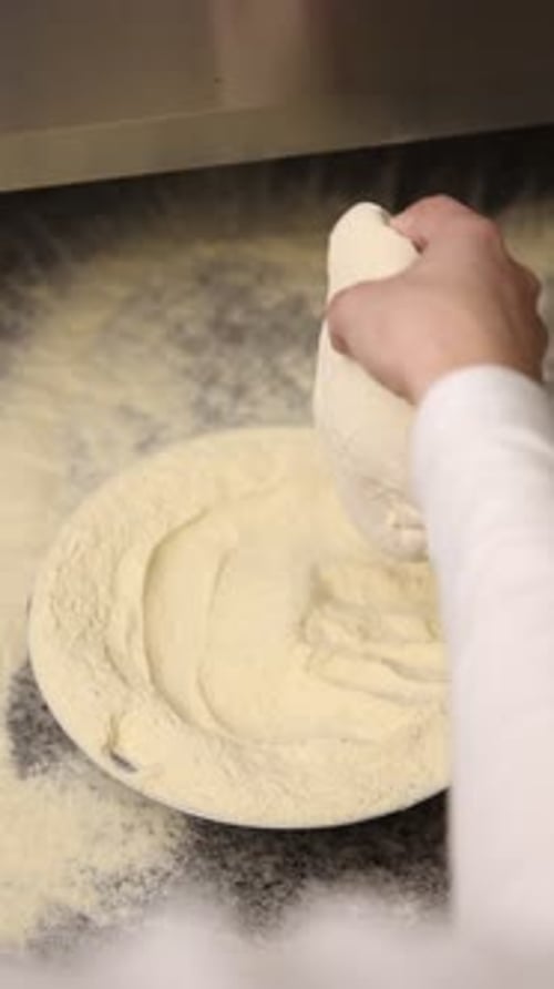 The chef makes delicious pizza in a professional kitchen.