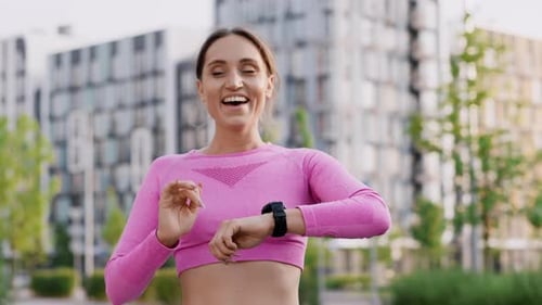 A Young Charming Girl Jogger Outdoors in the City Park Among Modern Residential Highrise Buildings A