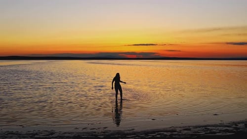 Person Walking in Ocean at Sunset
